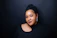 Portrait of a confident OnlyFans creator smiling against a sleek dark background with subtle gold accents.