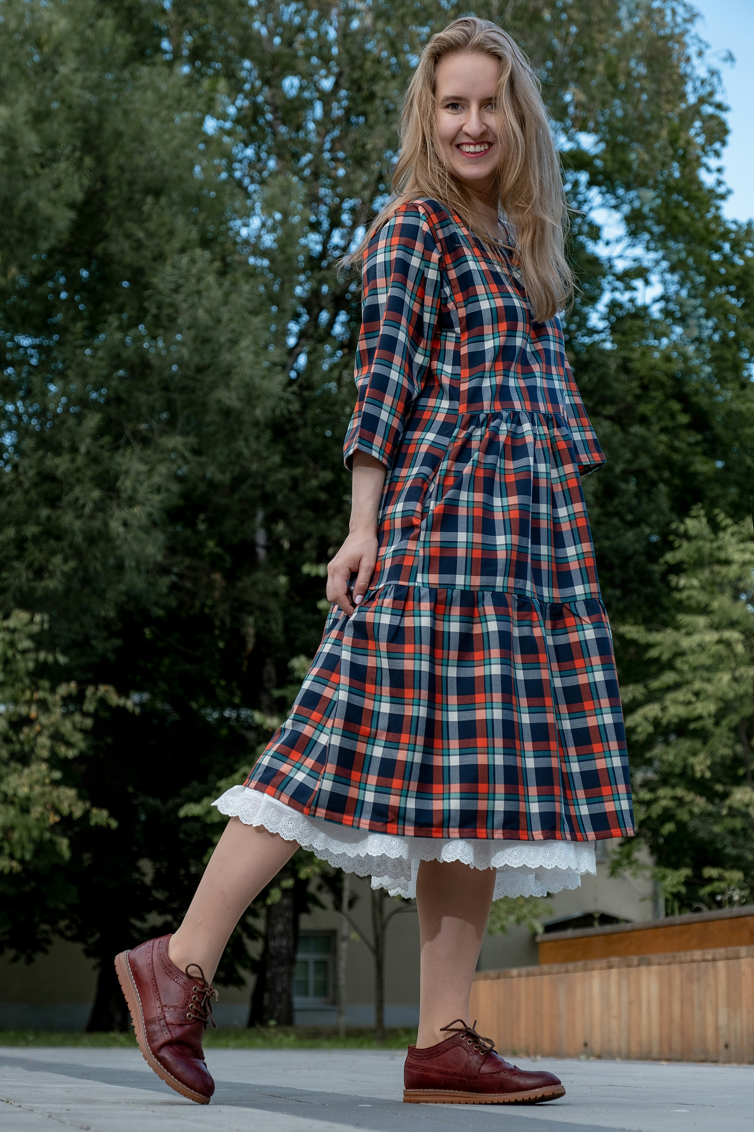 woman in blue and white plaid dress shirt and white skirt standing on brown wooden bench