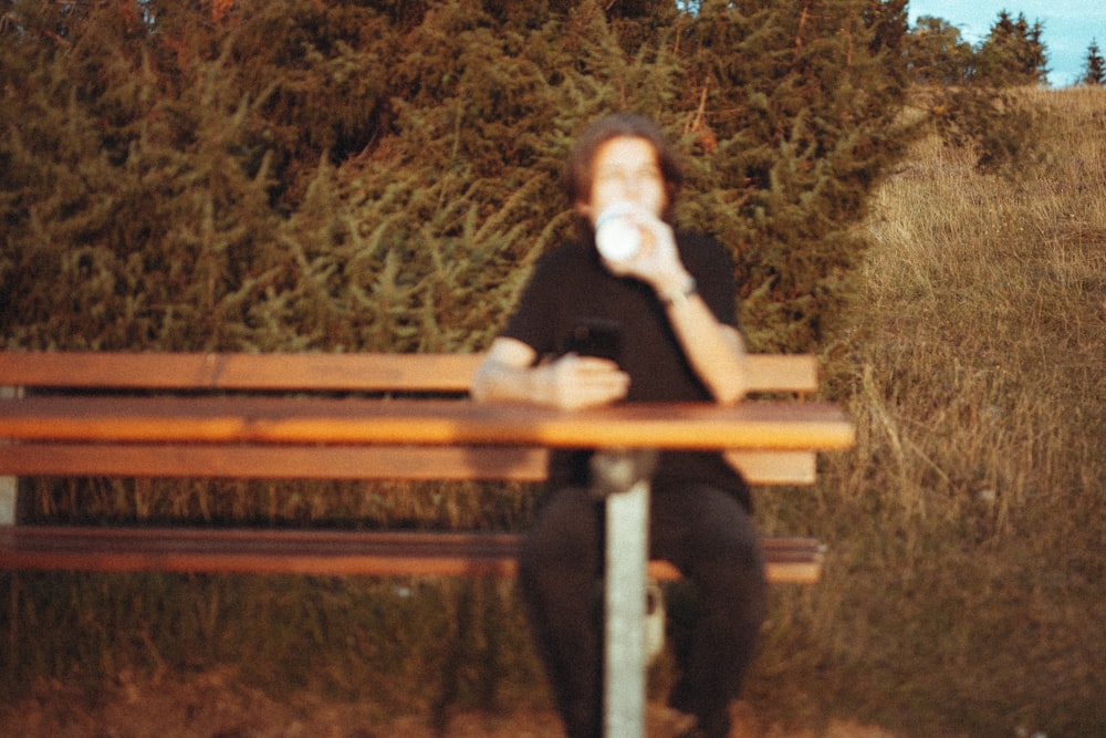 Frau im schwarzen Langarmhemd sitzt auf brauner Holzbank