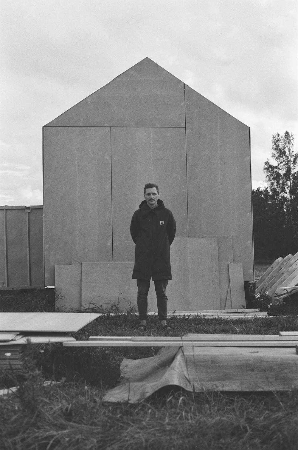 man in black coat standing near concrete wall
