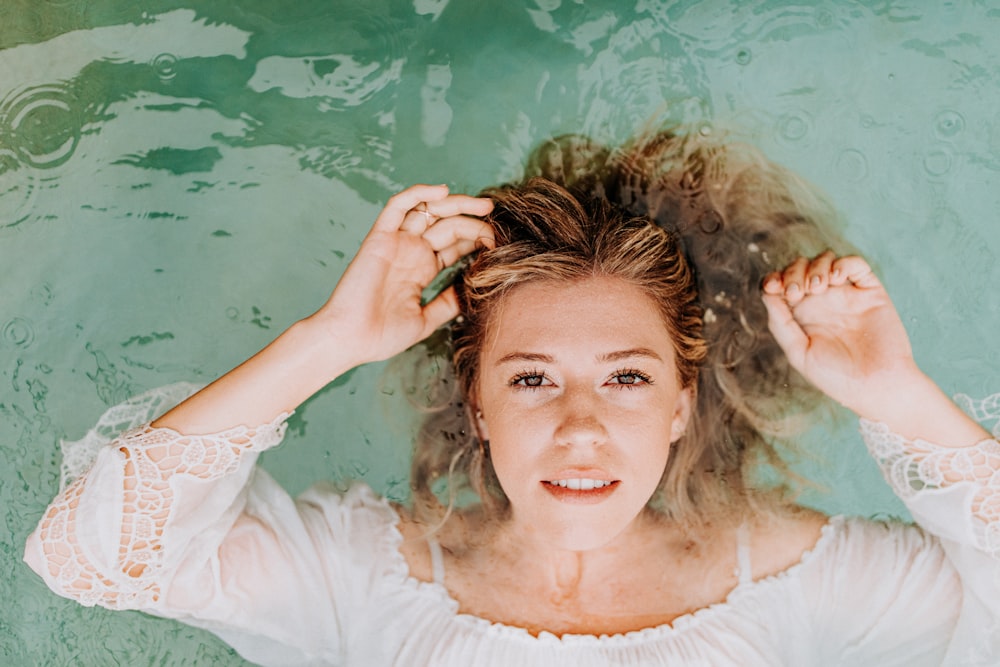 woman in white long sleeve shirt lying on water
