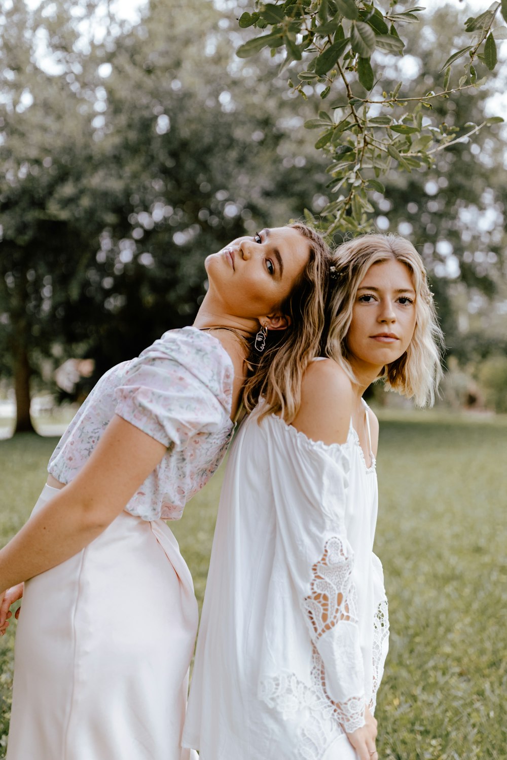 woman in white floral dress hugging girl in white dress