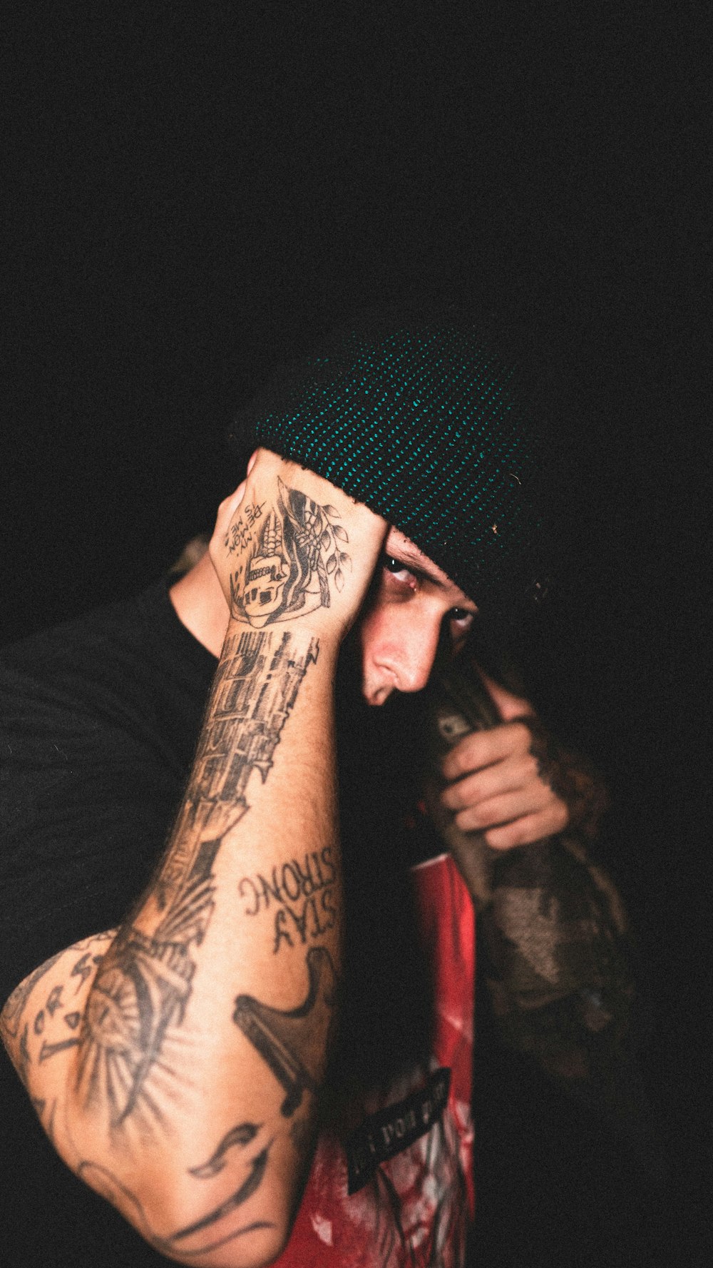 man in black knit cap with tattoo on his right arm