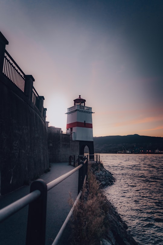 white and red lighthouse near body of water during daytime in Stanley Park Canada