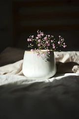 A close-up of a delicate ceramic vase in soft pastel hues holding fresh wildflowers.