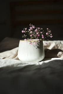 Close-up of a soft pink ceramic vase with subtle floral engravings on a wooden table