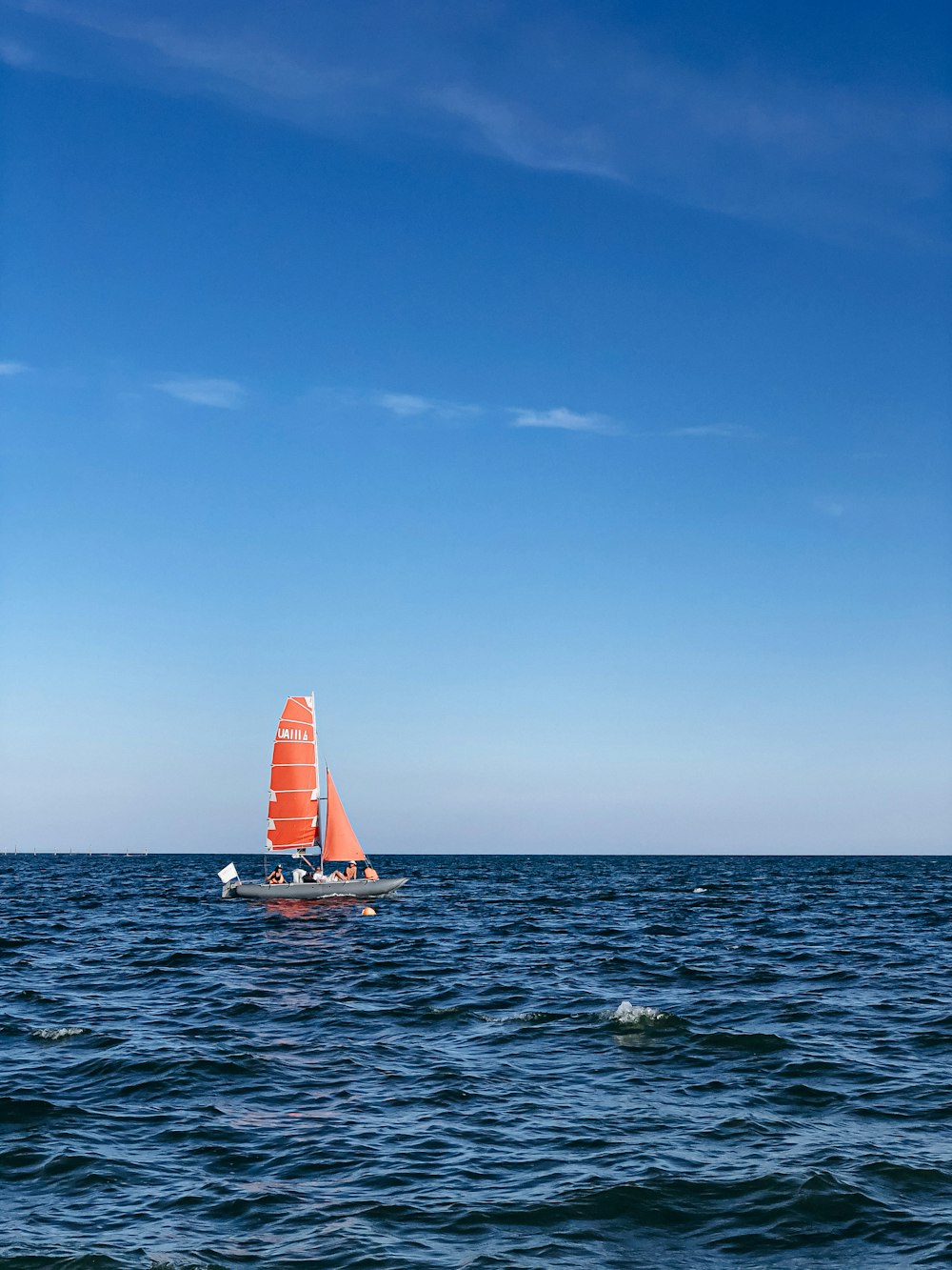 white sailboat on sea under blue sky during daytime