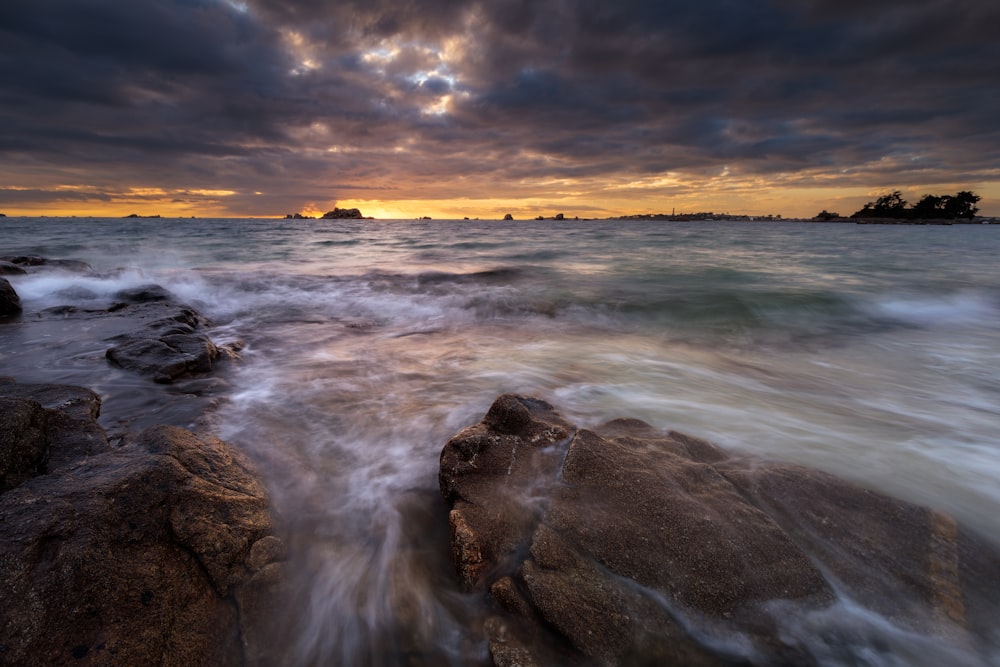 ocean waves crashing on rocks during sunset