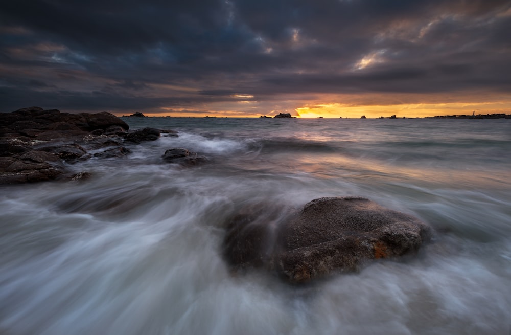 ocean waves crashing on shore during sunset