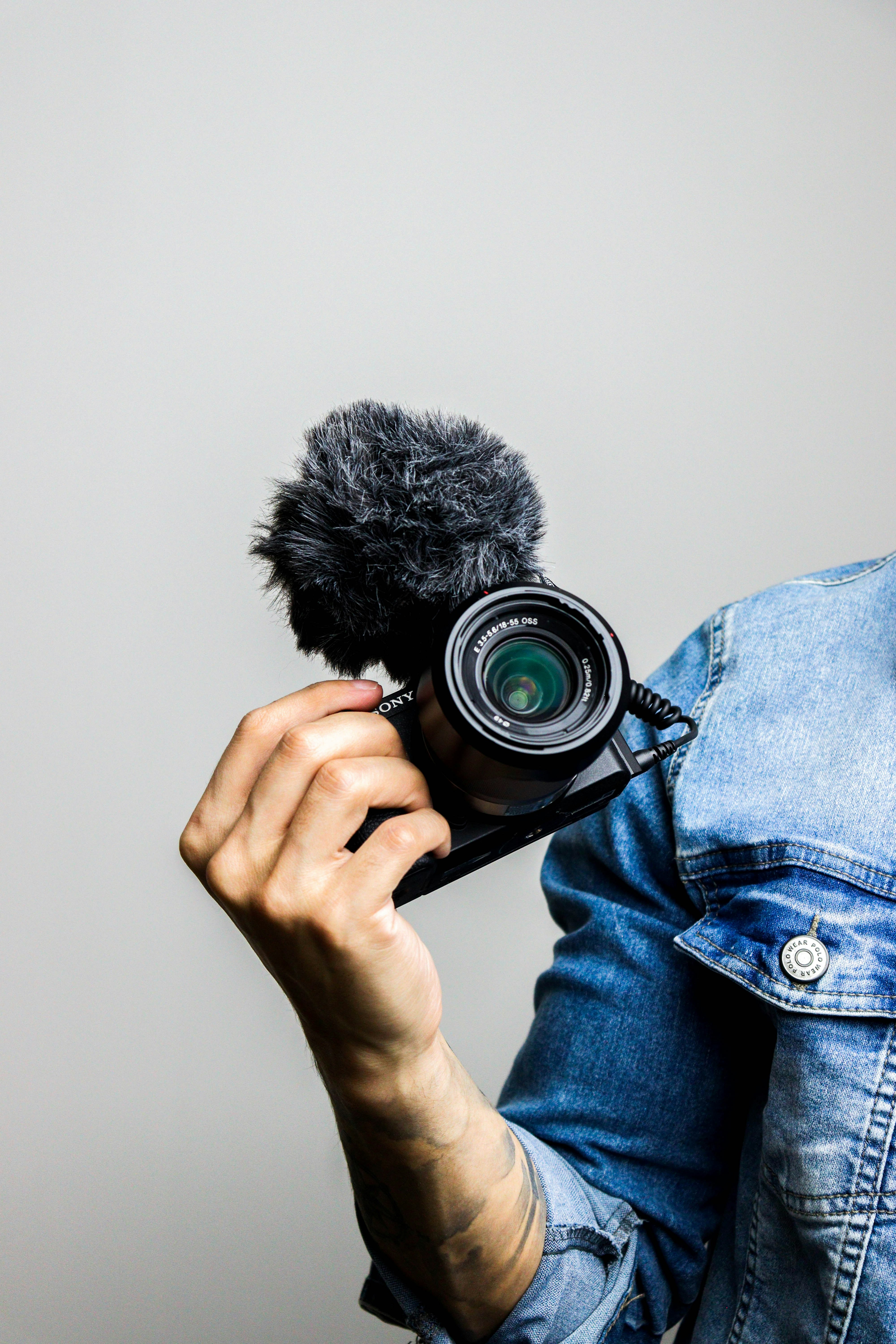 How to Spot When a Celebrity Interview Is Scripted (And What They Really Think) – person in blue denim jacket holding black dslr camera