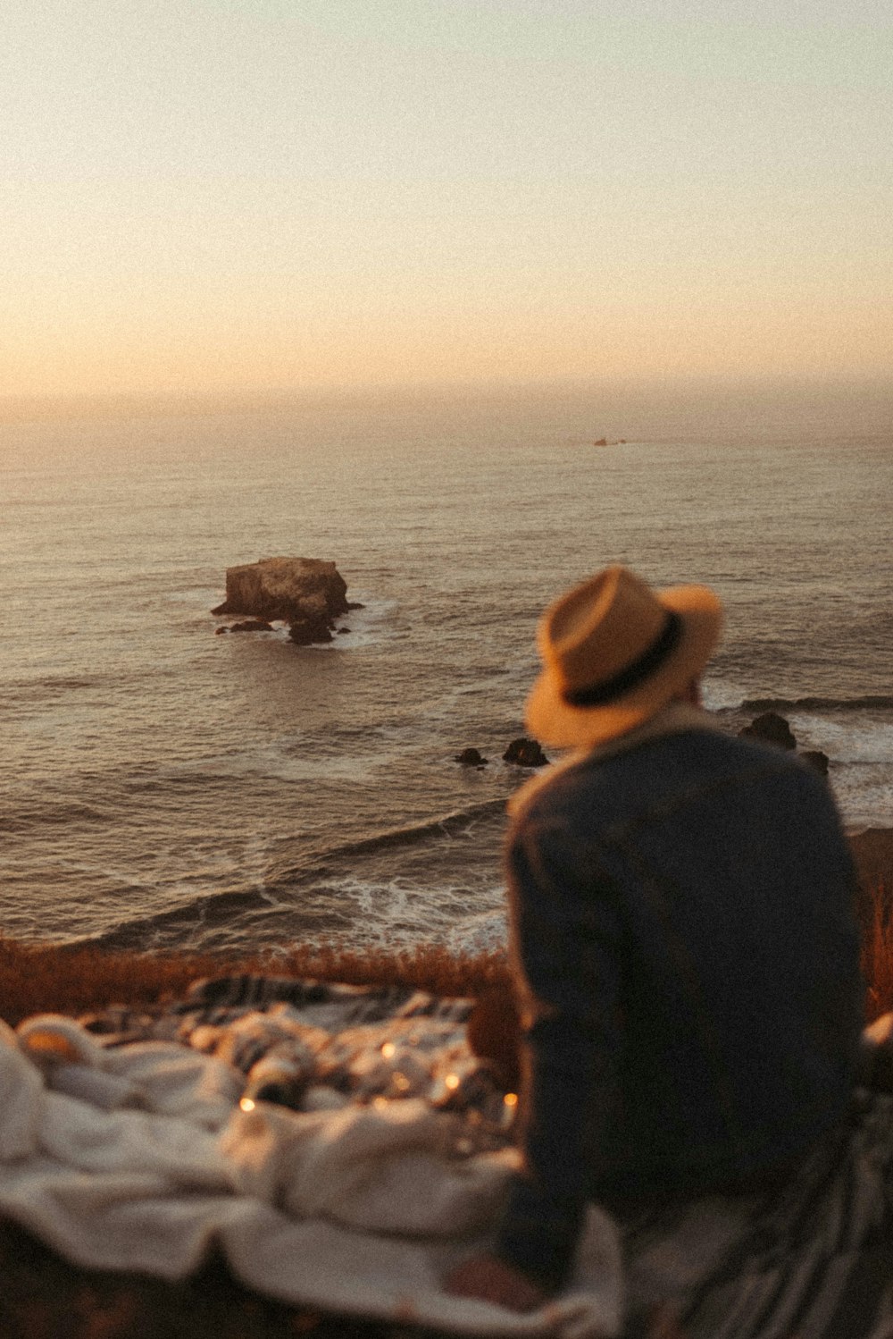 man in black jacket and brown hat standing on seashore during daytime