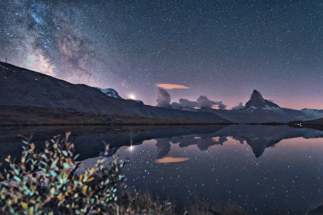 lake near mountain under blue sky during night time