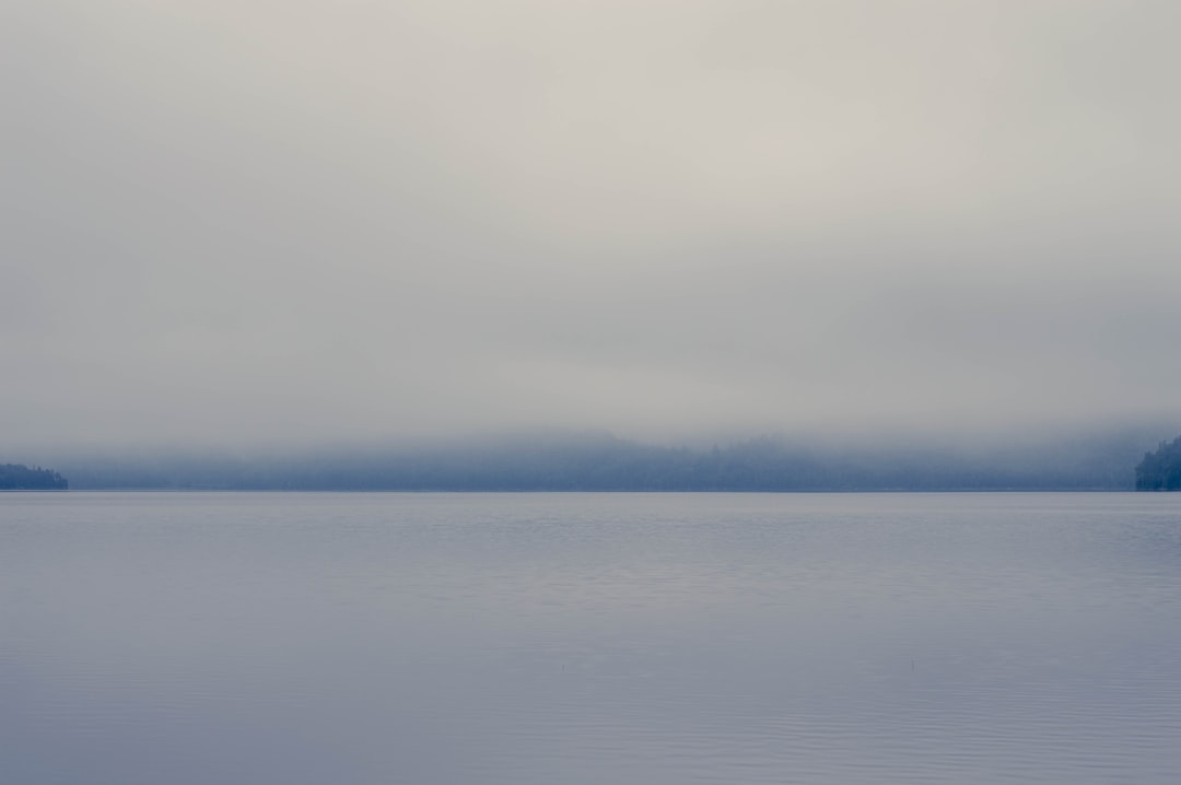 body of water under white clouds during daytime