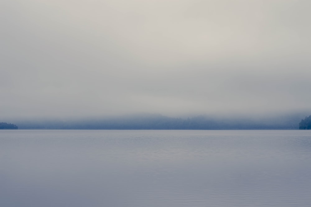 body of water under white clouds during daytime