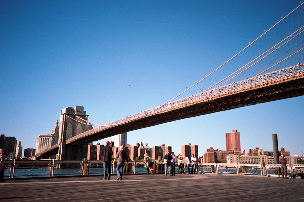 people walking on bridge under blue sky during daytime