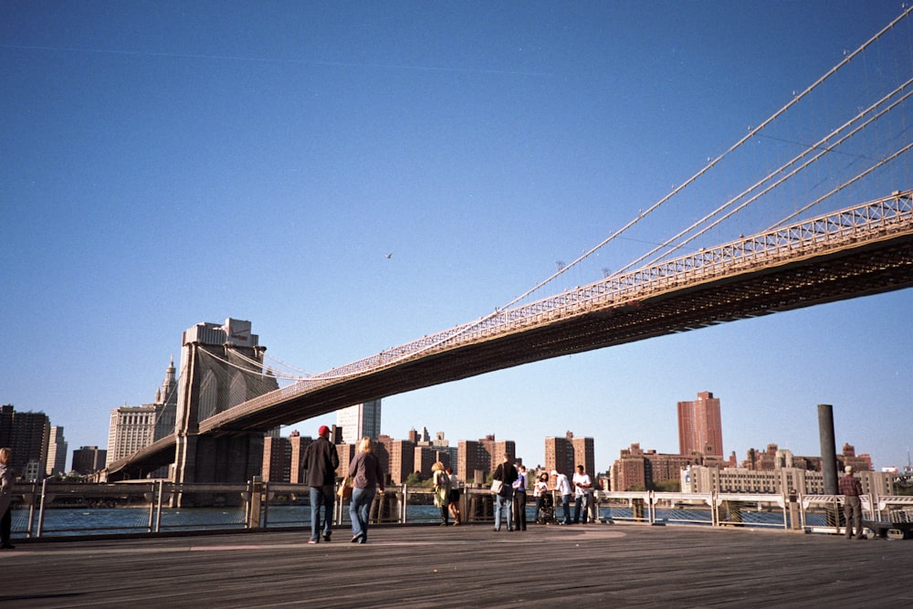 people walking on bridge under blue sky during daytime