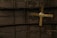 A ceiling fan with four wooden blades is mounted against a corrugated metal ceiling. The blades appear slightly worn and the metal ceiling has a dark, industrial look with visible lines and sections.