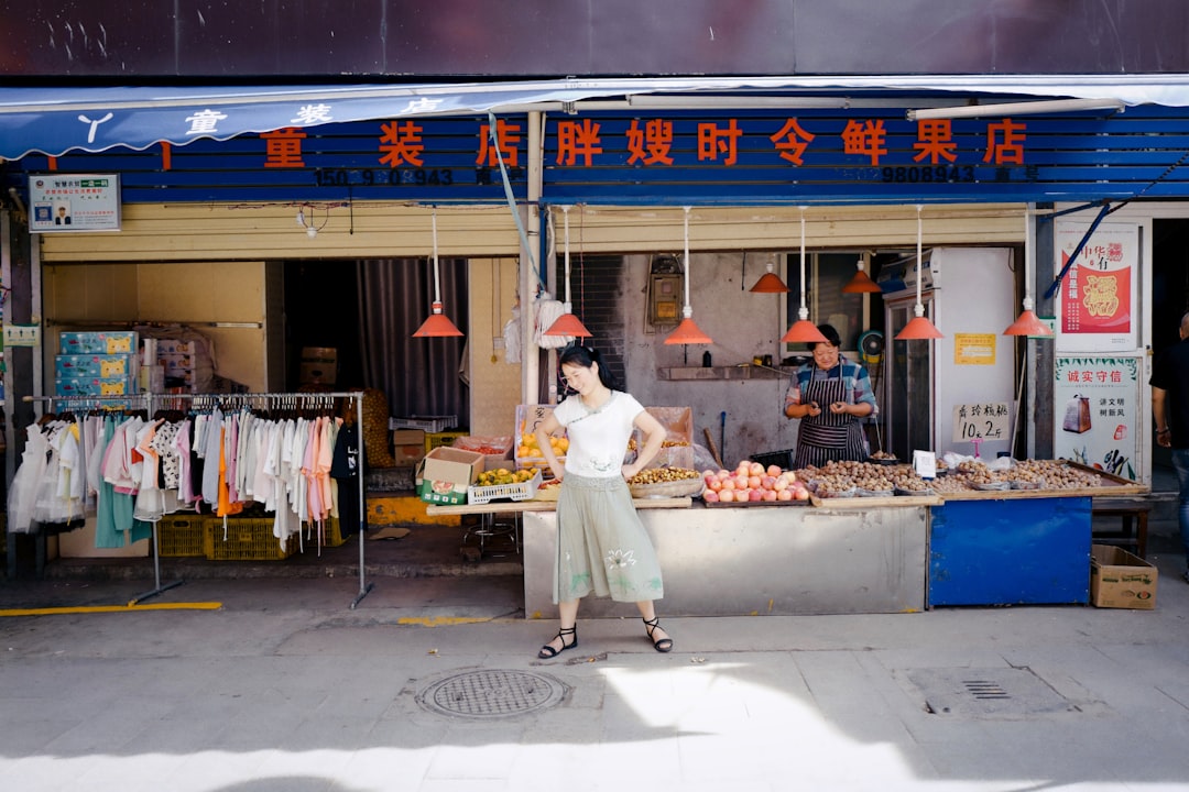 man in white long sleeve shirt and white pants standing in front of food stall during