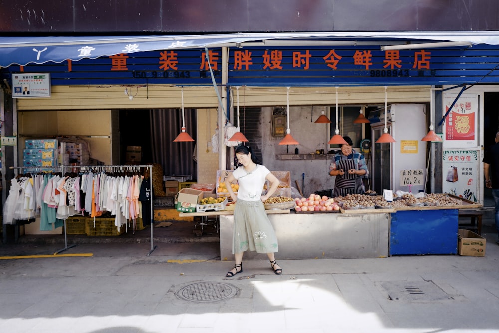 man in white long sleeve shirt and white pants standing in front of food stall during