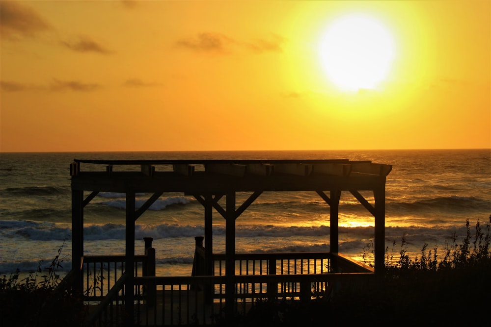 silhouette of person standing on wooden dock during sunset