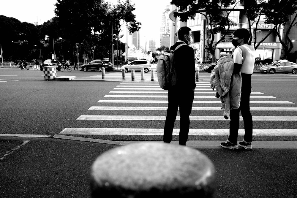 Foto en escala de grises de hombre y mujer caminando por el carril peatonal