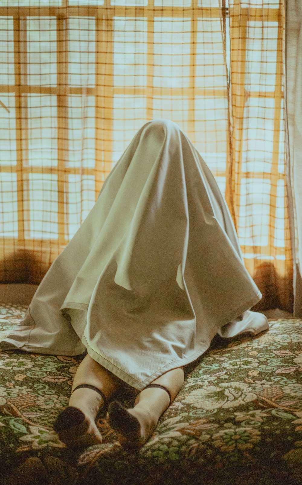 person in white robe sitting on white and black floral area rug