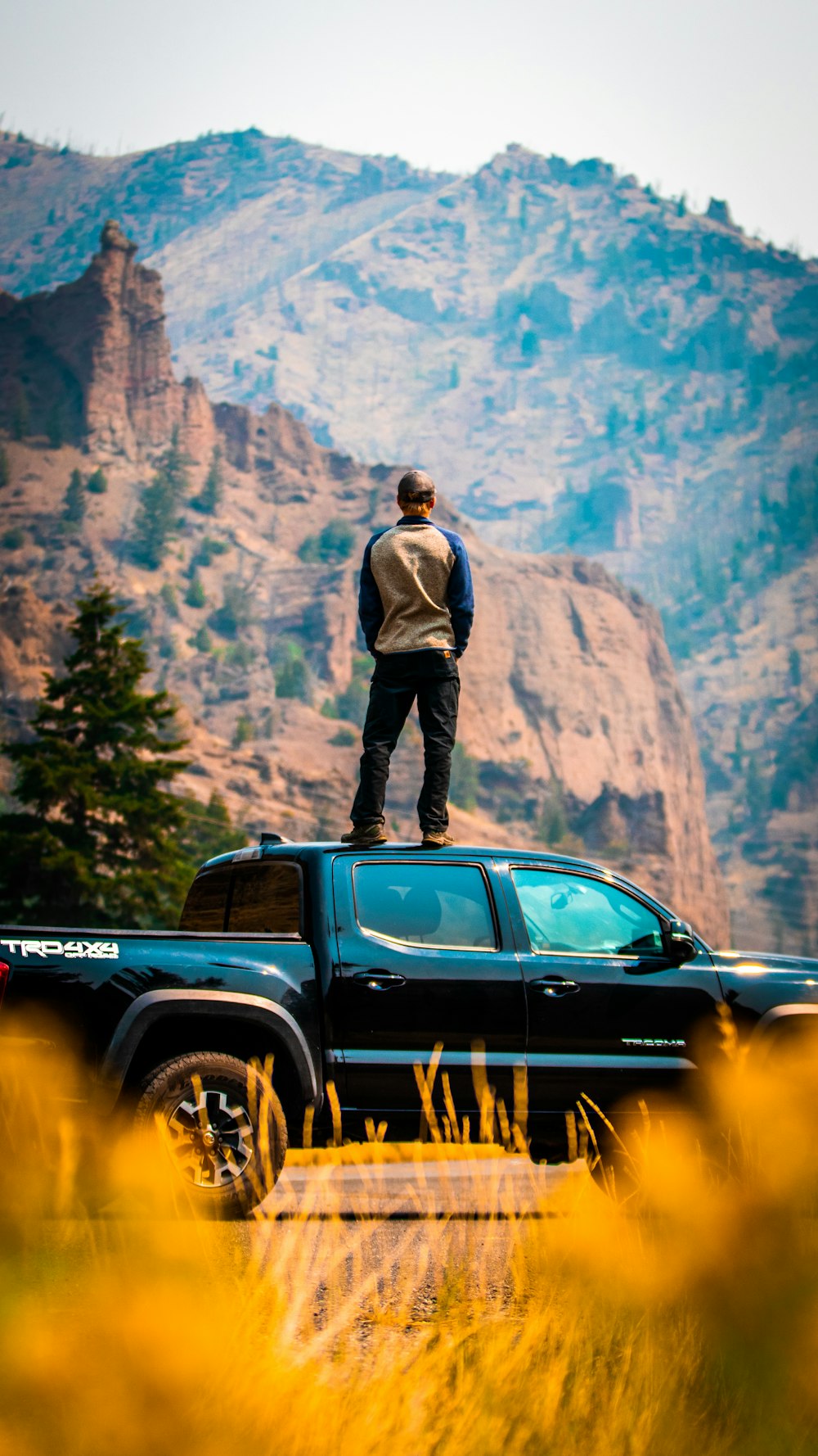 man in gray jacket standing on black car