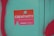 A sticker with a gradient from orange to pink that reads 'Creativity Express Yourself' is pasted on a teal surface. The sticker also features a design with a circle and a triangle, and is surrounded by red graffiti on the left and bottom edges of the image.