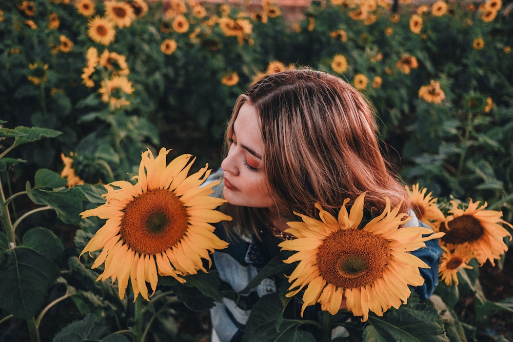 woman in black and white floral shirt holding sunflower