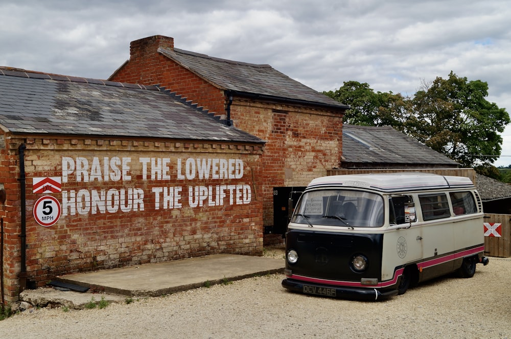 red and white volkswagen t-1 parked beside brown brick wall during daytime