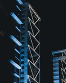 A futuristic skyscraper with intricate facade patterns glowing under twilight.