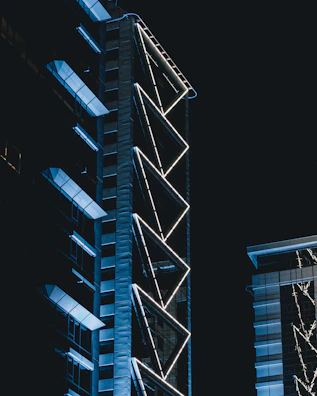 A futuristic skyscraper with intricate facade patterns glowing under twilight.