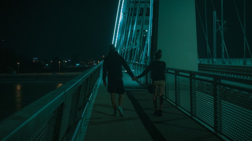 Frau in schwarzer Jacke geht nachts auf der Brücke