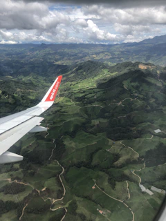A scenic view of an airplane flying over lush green mountains.