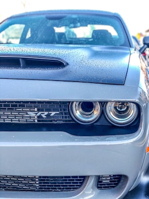 Close-up of a gleaming Dodge Challenger SRT hood with sharp black-and-white contrast.