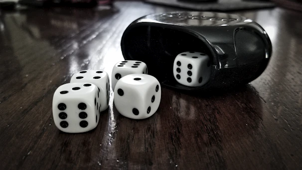 Hand-stitched leather würfelbecher (dice cup) displayed next to wooden dice on a table.