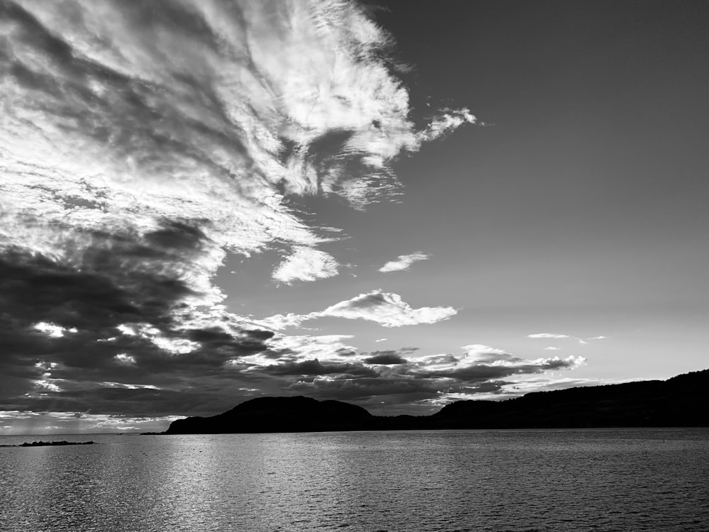 grayscale photo of body of water and mountains