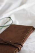 Notebook with handwritten reflections beside a pair of glasses on a black surface