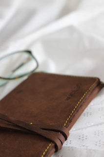 A pair of vintage-inspired eyeglasses resting on an open journal with handwritten notes.