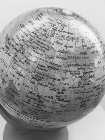 A monochromatic image of a globe displaying geographical details of Europe, Asia, and parts of Africa. Countries and cities are labeled, with boundaries clearly marked. The continents and countries are depicted in a black and white color scheme.