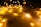 Fairy lights drape softly over a sheet of paper displaying religious symbols and text about love from Romans 5:8. The warm glow of the lights creates a peaceful and inviting atmosphere.