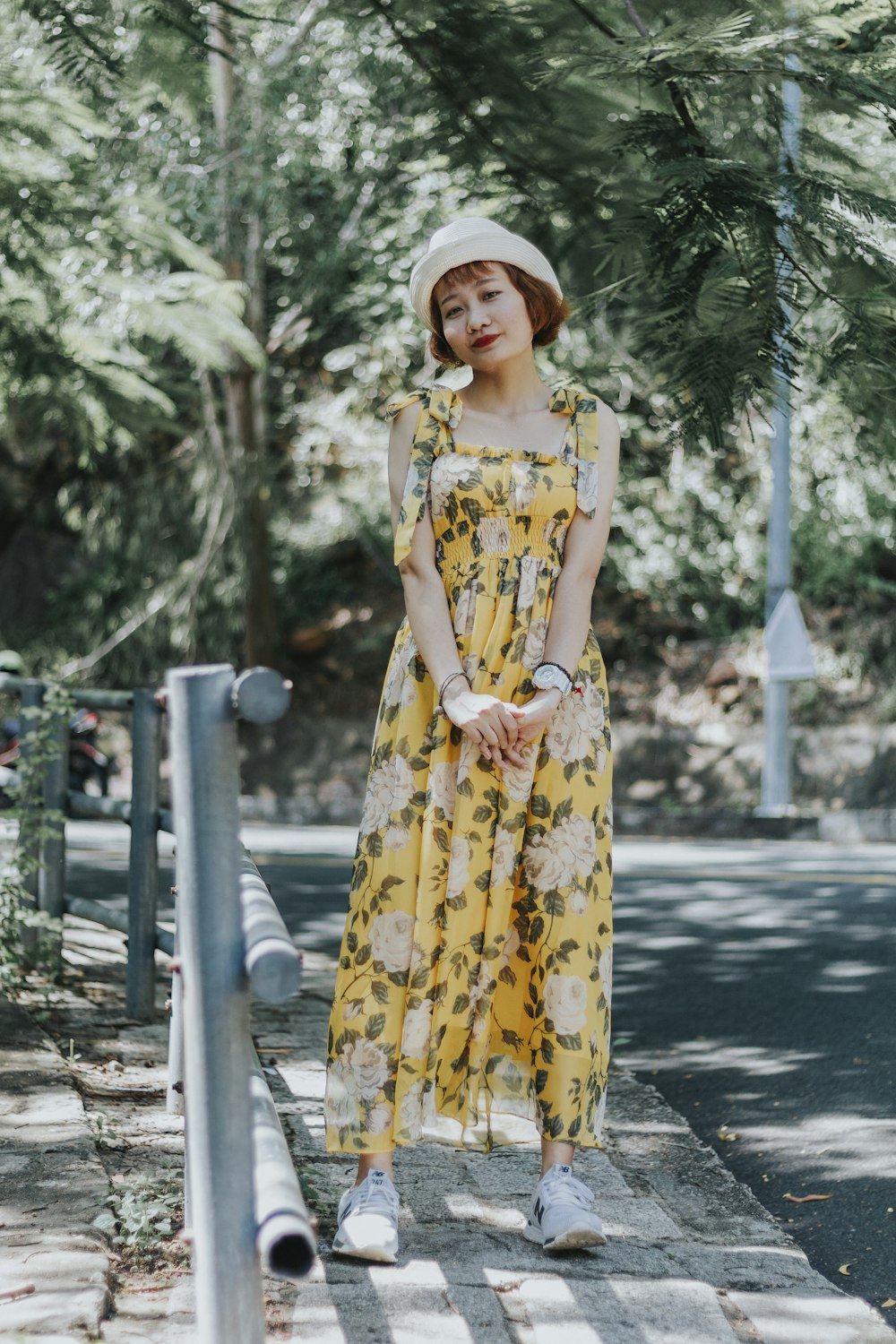 woman in yellow and white floral dress standing on road during daytime