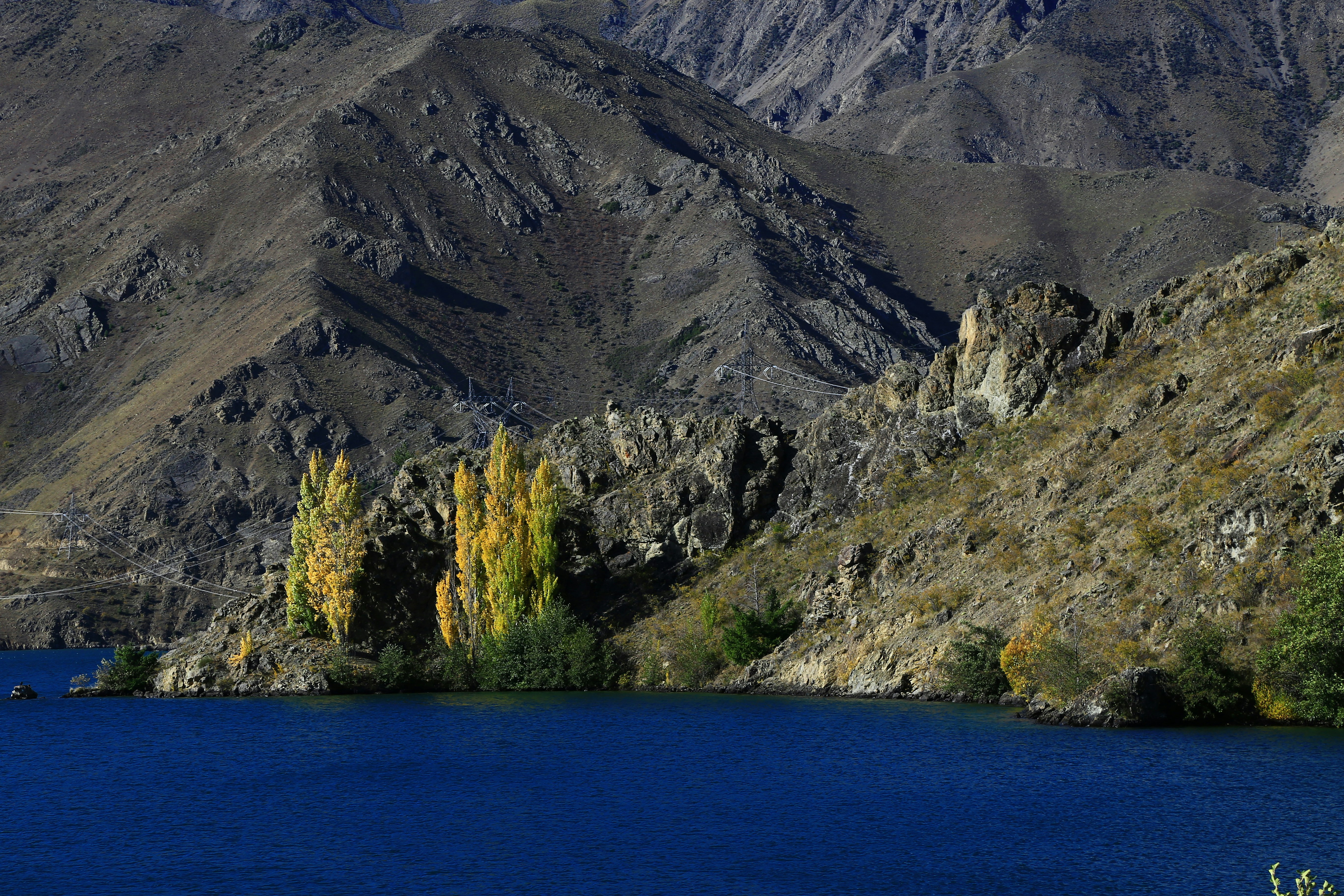 green and brown mountain beside blue sea during daytime