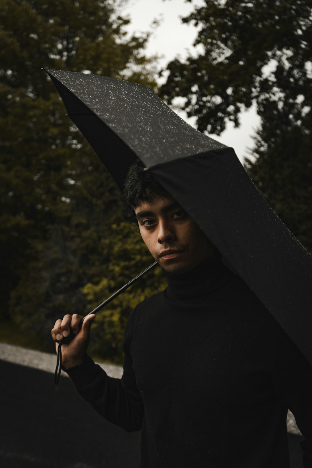 man in black hoodie holding umbrella