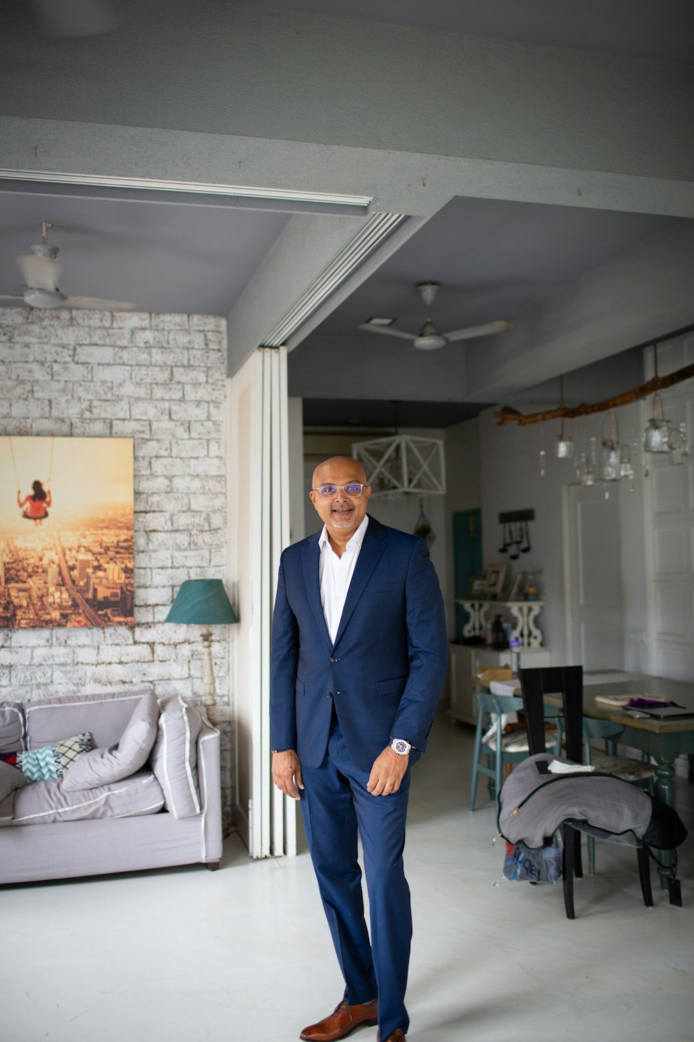 man in black suit standing near white sofa