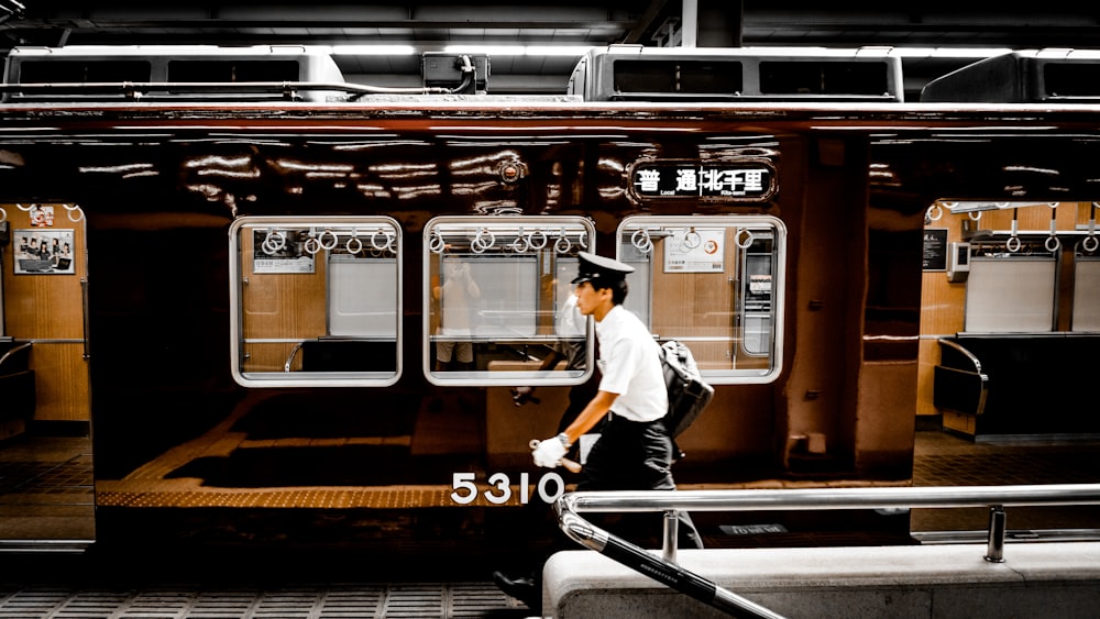 man in white dress shirt and blue denim jeans standing on train station