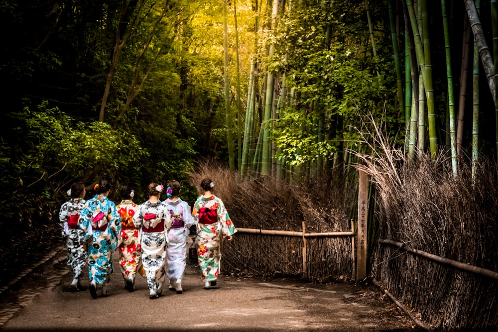 people in white and red kimono walking on pathway between trees during daytime