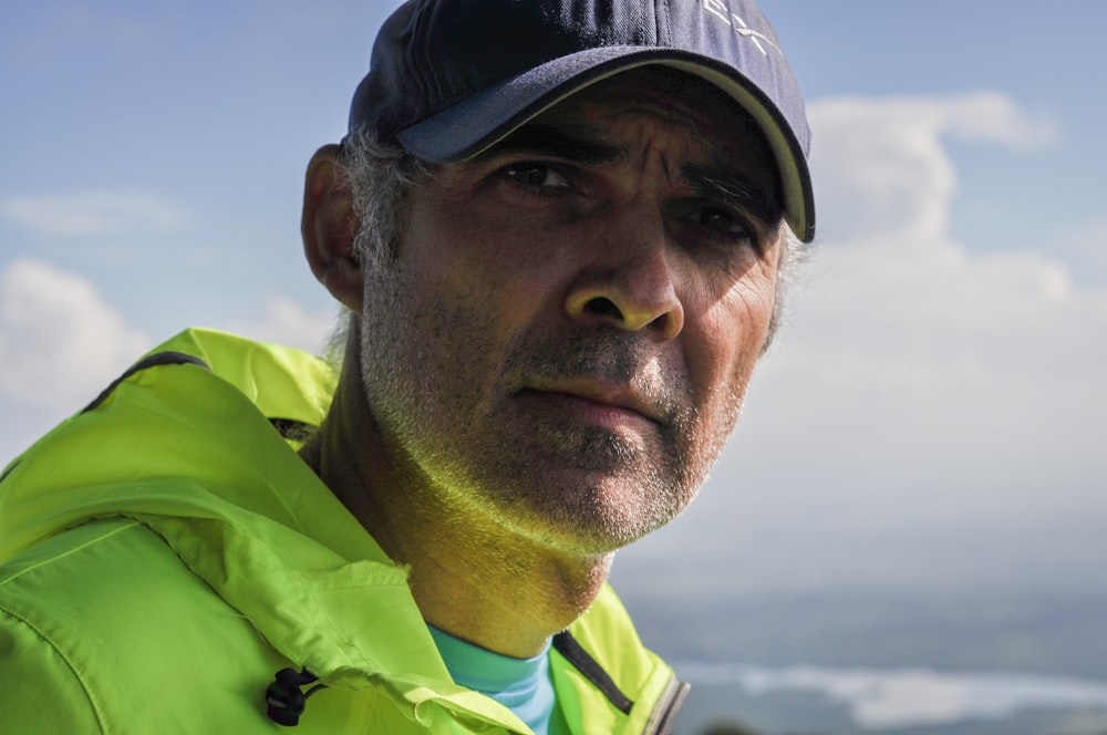 Homme en veste verte et blanche portant une casquette noire