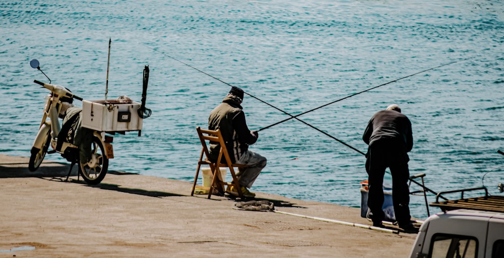 昼間、海で釣りをする黒いジャケットと黒いズボンを着た男
