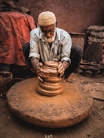 man in white and black stripe dress shirt and brown hat sitting on brown clay pot